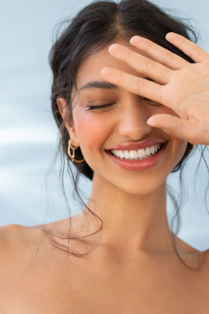 Woman smiling with a hand resting on her forehead
